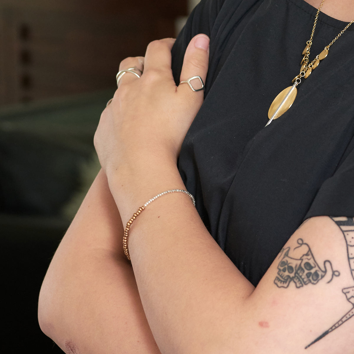 A close up of a woman's arm and the gold and silver bracelet on her wrist.