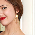 A close up of a woman's ear with a gold and silver dangling earring.