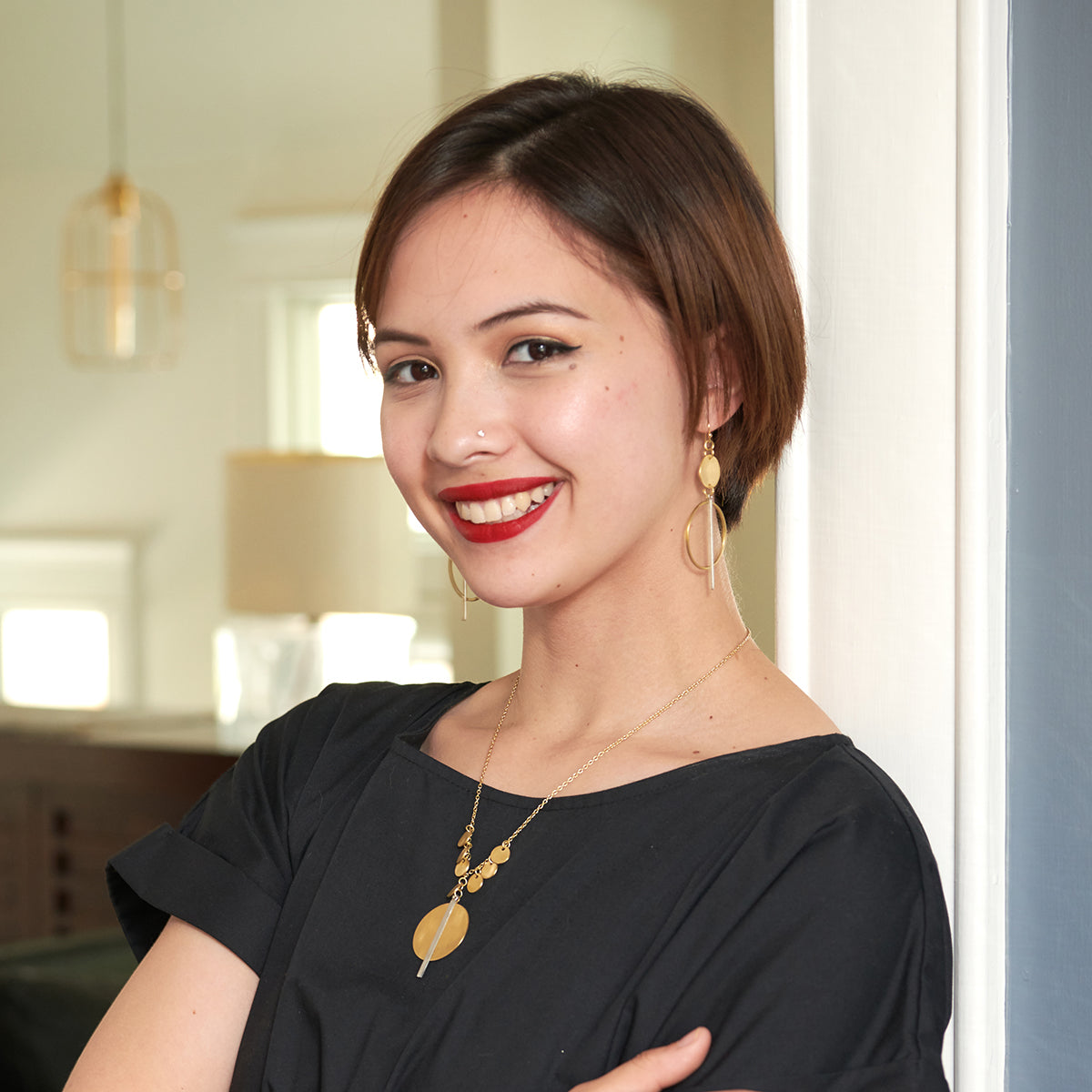 A young woman in a black shirt smiles while showing off her gold and silver jewelry.