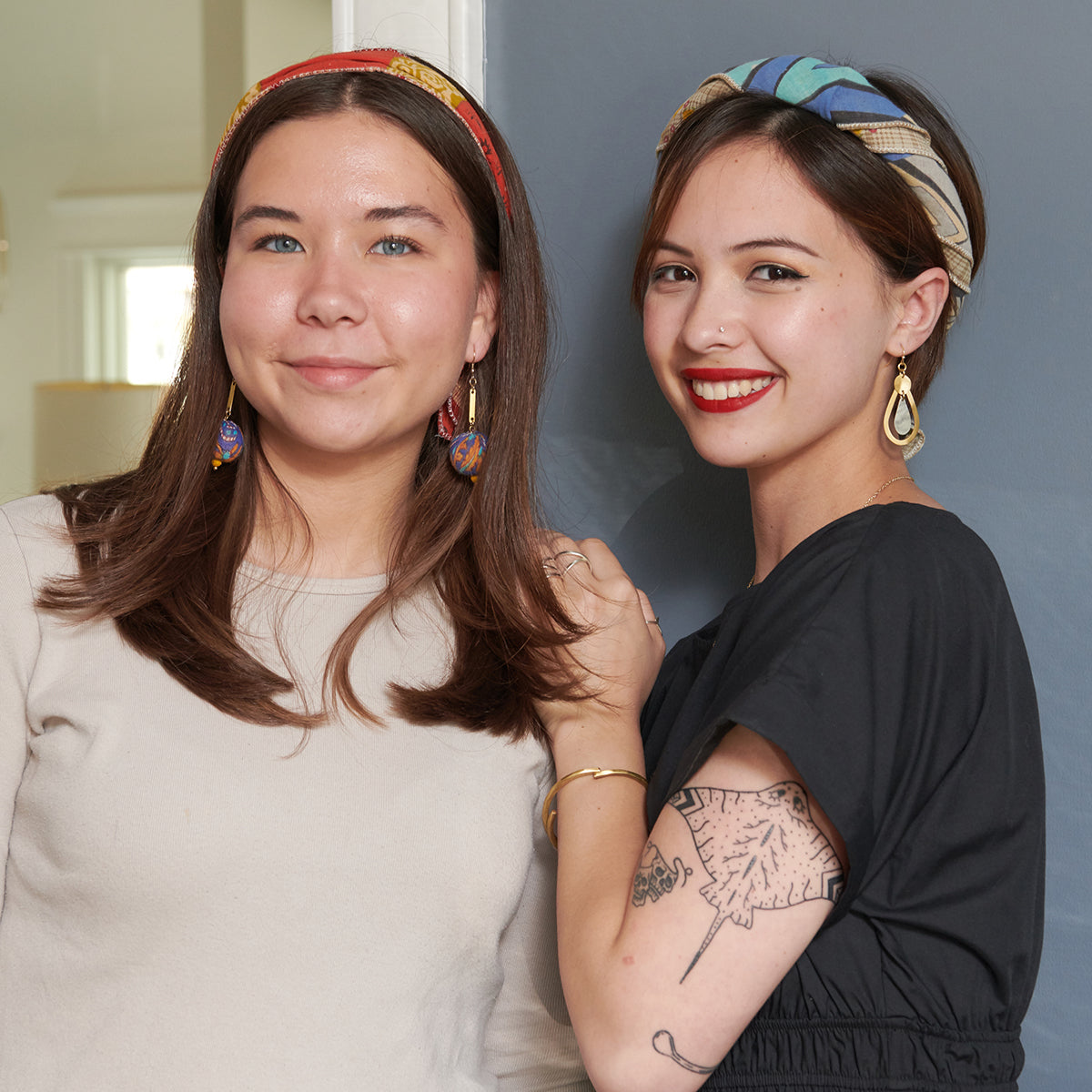 Two young women smile while modeling fair trade jewelry.