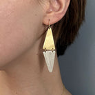 A close up of a gold and silver diamond-shaped earring in a woman's ear.