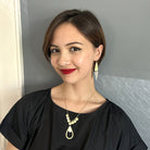 A young woman in a black shirt smiles while showing off her gold and silver jewelry.