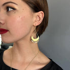 A close up of a woman's ear with a gold dangling earring.