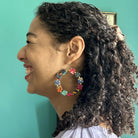 A young woman looks to the left and laughs while showing off her earrings.