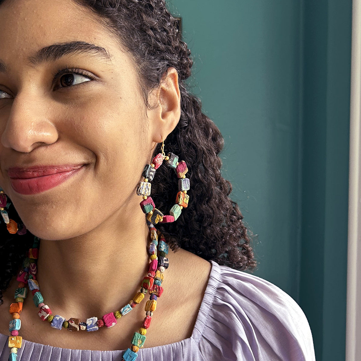 A close up of a young woman looking to the left and her beaded earrings.