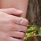 A close up of a woman's hand resting on her elbow, showing the details of her two silver rings.