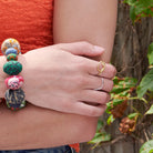 A woman rests her hand on her elbow, showing off her two rings on her fingers.