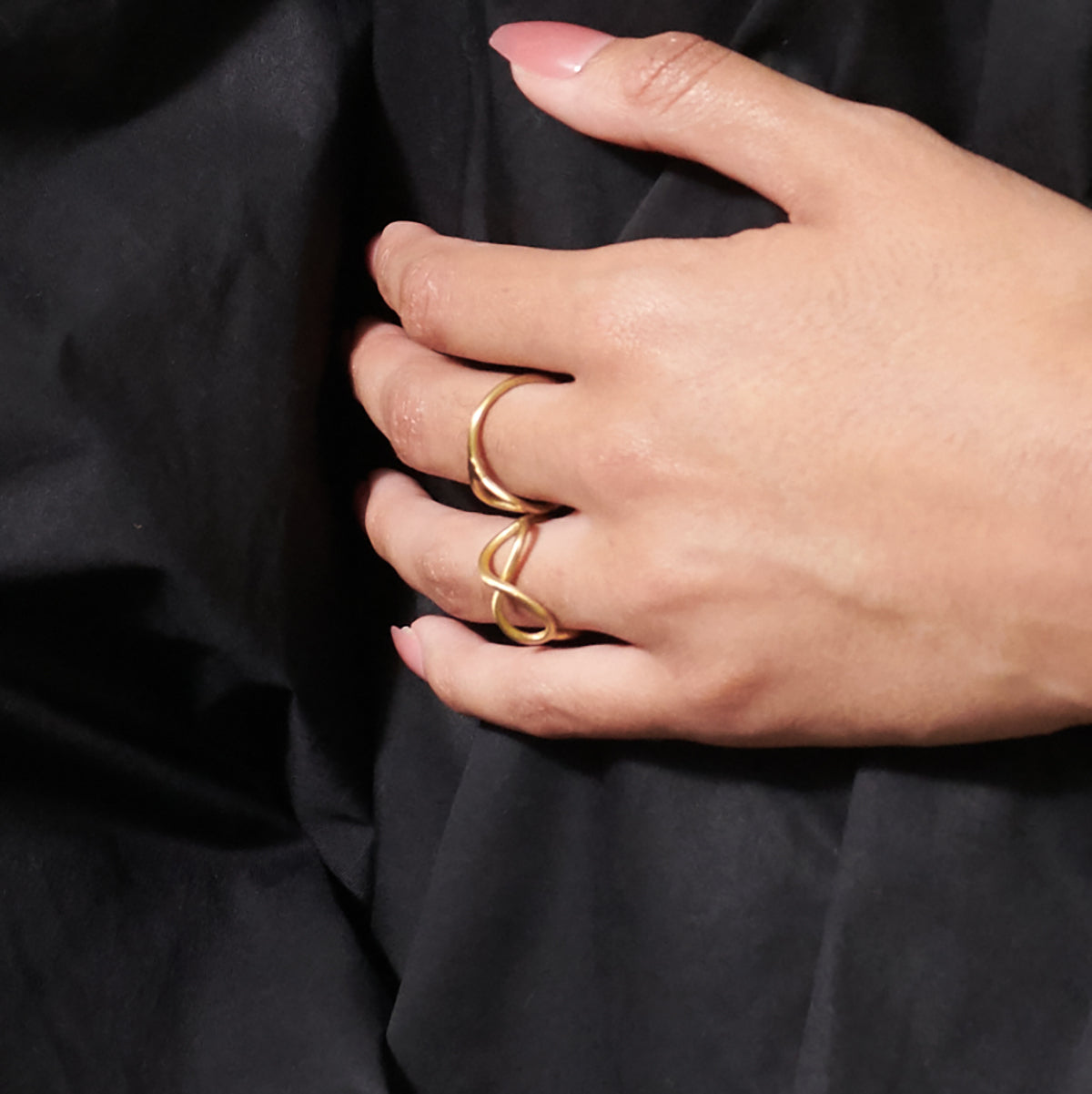 A closeup of a woman's hand and the gold rings on her fingers.