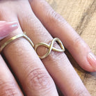 A close up of a gold infinity ring on a woman's finger.