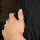 A close up of a woman's hand resting on her black shirt, showcasing a silver ring on her thumb.