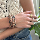 A woman rests her hand on her elbow, showing off her gold and silver rings.