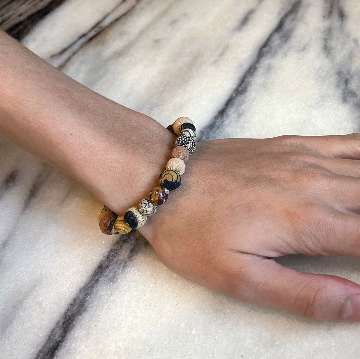 A close up of a woman's wrist and her beaded bracelet.