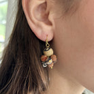 A close up of a woman's ear and the beaded neutral-toned earring she is wearing.