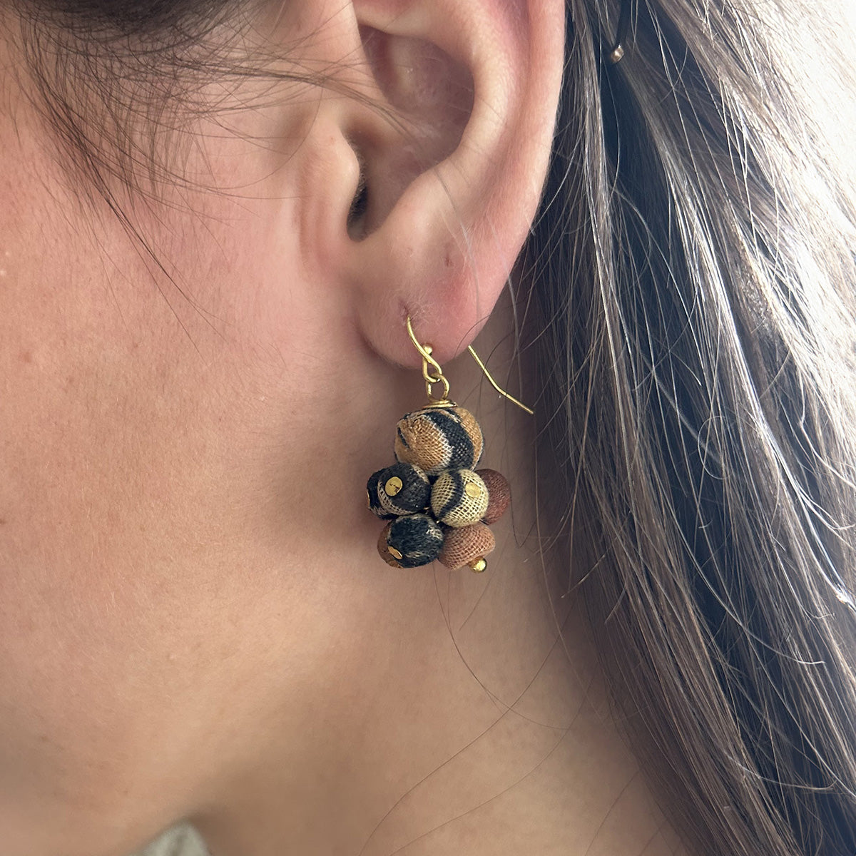 A close up of a woman's ear and the beaded neutral-toned earring she is wearing.