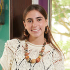 A woman in a beige, crocheted shirt smiles at the camera.