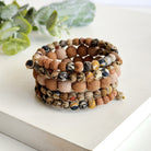 A beaded cuff bracelet rests on a white surface with a green cactus in the background.