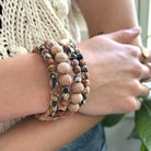 A close up of a woman's wrist and her beaded, neutral-toned bracelet.