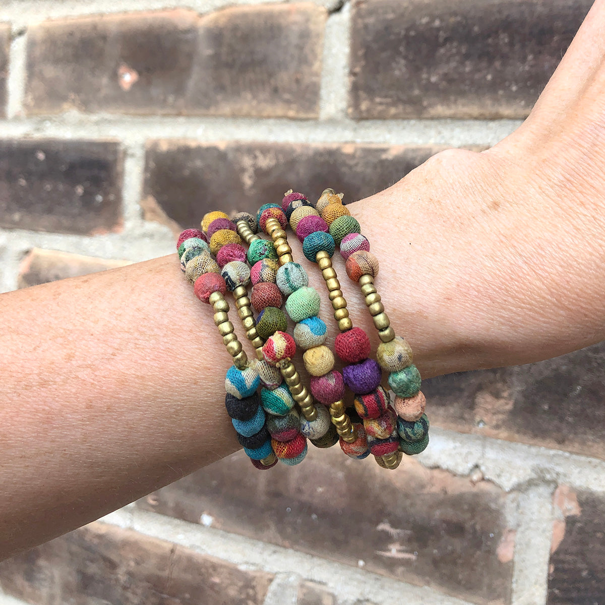 A close up of a woman's arm and the stack of six beaded bracelet she is wearing.