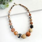 A beaded necklace of multi-toned brown & tan beads against a white background.