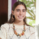 A woman in a white crocheted top and tan-colored beaded jewelry smiles.