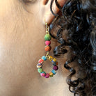 A close up of a woman's ear and the beaded, multicolor earring she is wearing.