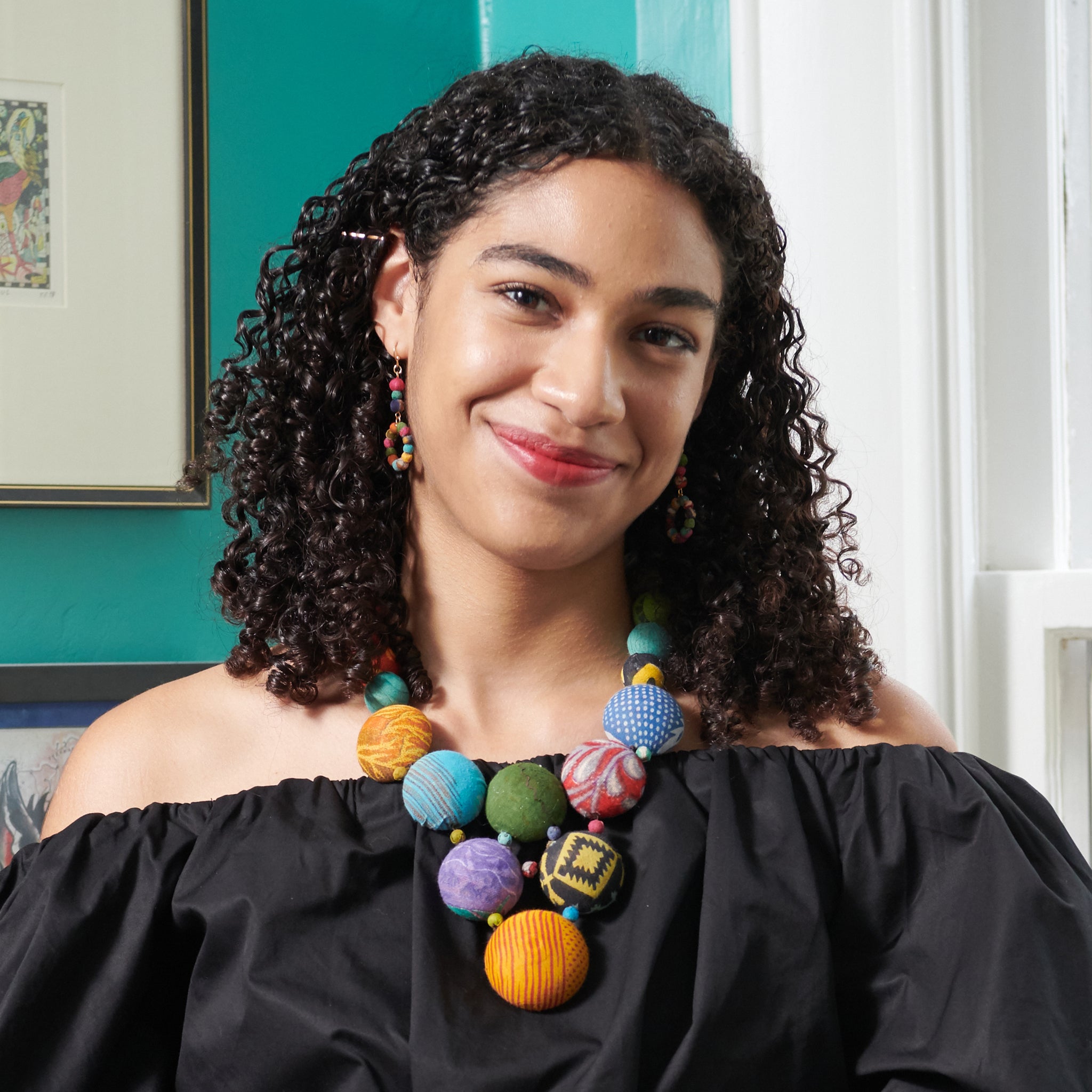 A woman in a black shirt and multicolor, beaded jewelry smiles.