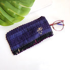 A dark indigo eyeglass case against a white background, with a pair of red eyeglasses sticking out of the pouch.