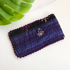 A dark indigo quilted eyeglass case against a white background.