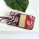 A plum, yellow & red eyeglass case against a white background, with a pair of red eyeglasses sticking out of the pouch.