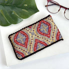 A yellow & red eyeglass case against a white background with a pair of red eyeglasses in the background.