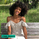 A model in a white dress smiles while showing off her earrings.