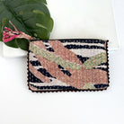 A zebra-patterned rectangular pouch against a white background with a large leaf in the background.