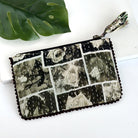 A black and grey rectangular pouch against a white background with a large leaf in the background.