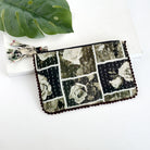 A black and grey rectangular pouch against a white background with a large leaf in the background.