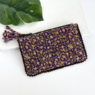 A purple floral rectangular pouch against a white background with a large leaf in the background.