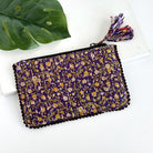 A purple floral rectangular pouch against a white background with a large leaf in the background.