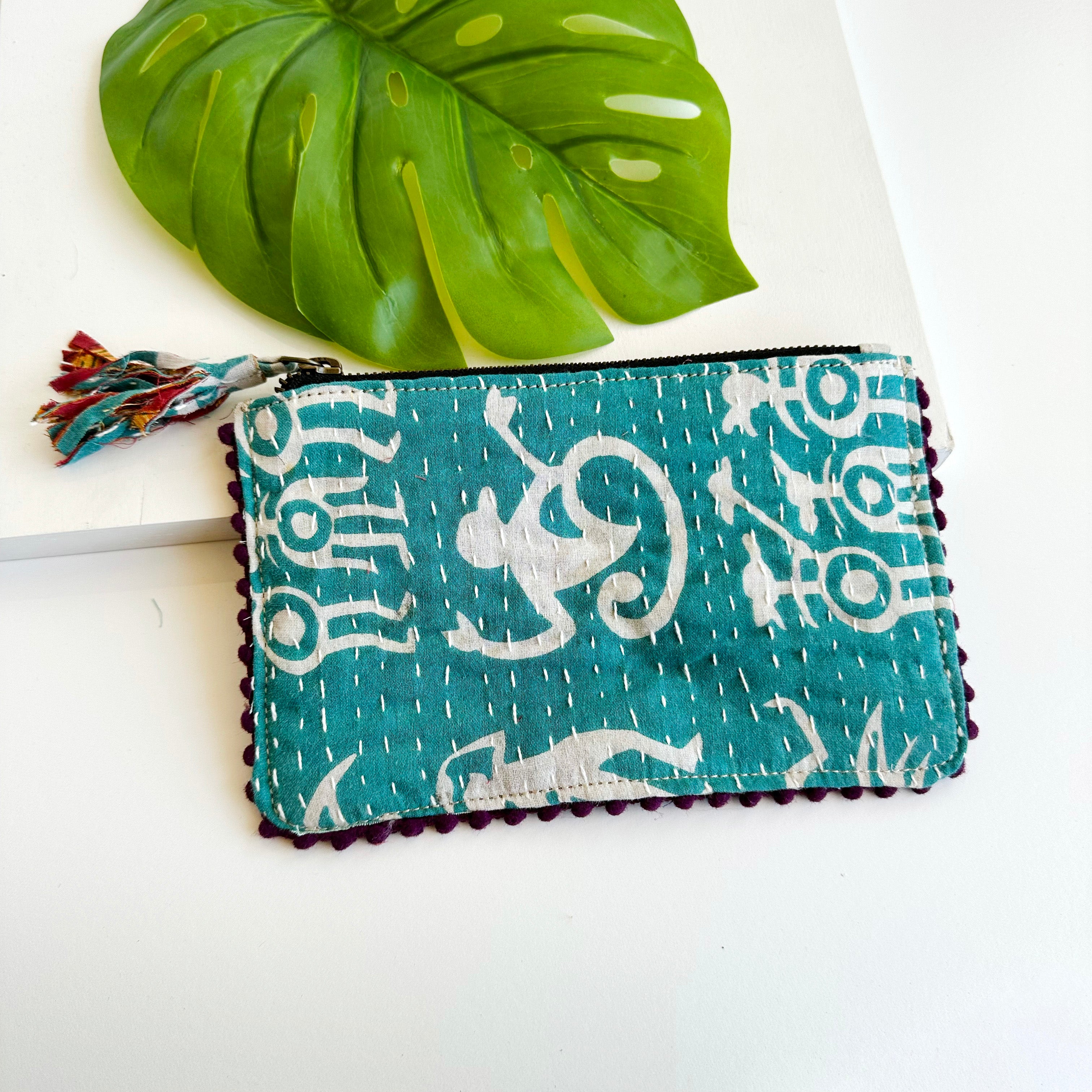 A blue and white rectangular pouch against a white background with a large leaf in the background.