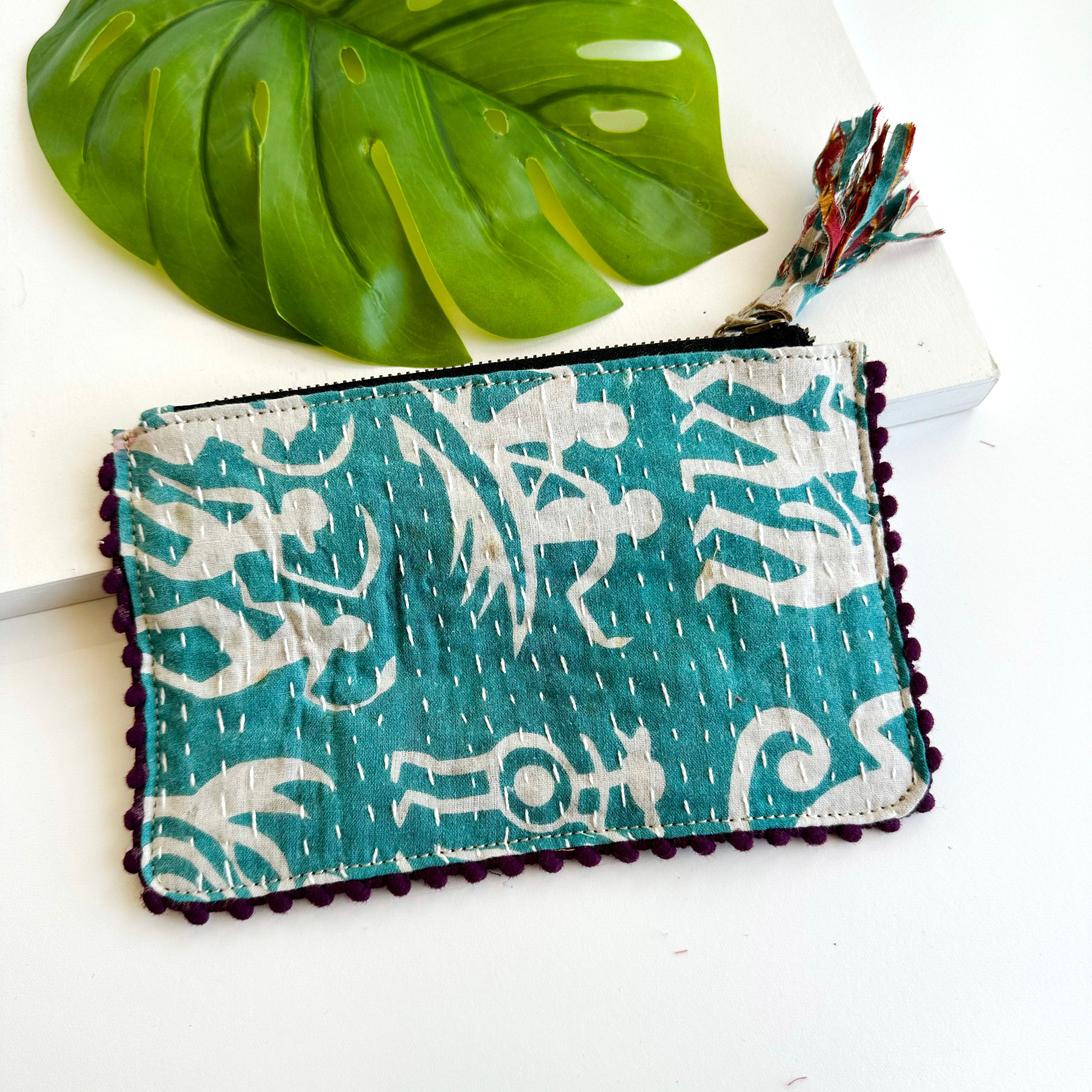 A blue and white rectangular pouch against a white background with a large leaf in the background.