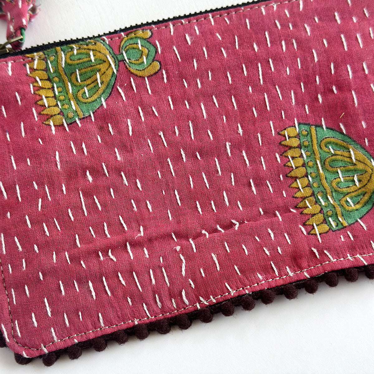 A close up of a pink rectangular pouch with white Kantha stitching.