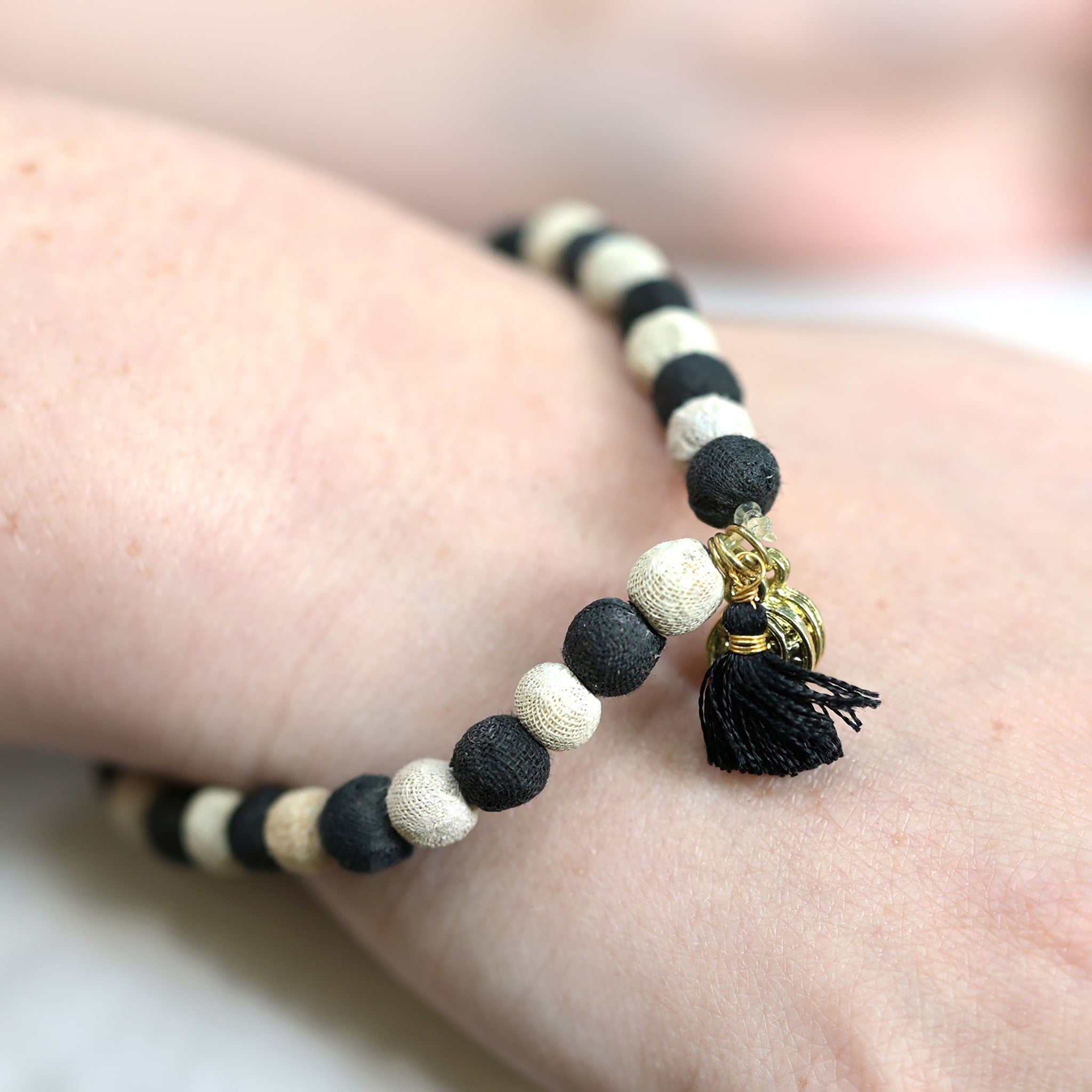 A close up of a woman's wrist and her black and white beaded bracelet.