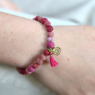 A close up of a woman's wrist and the pink beaded bracelet she wears.