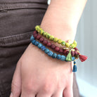 A close up of a woman's wrist and the green, red and blue beaded bracelets she is wearing.