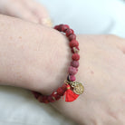 A close up of a woman's wrist and the red beaded bracelet she wears.