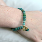 A close up of a woman's wrist and the green beaded bracelet she wears.