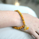 A close up of a woman's wrist and the yellow beaded bracelet she wears.