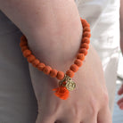 A close up of a woman's wrist and the orange beaded bracelet she wears.