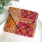 A embroidered tan, pink and orange envelope-style pouch is shown against a white background.