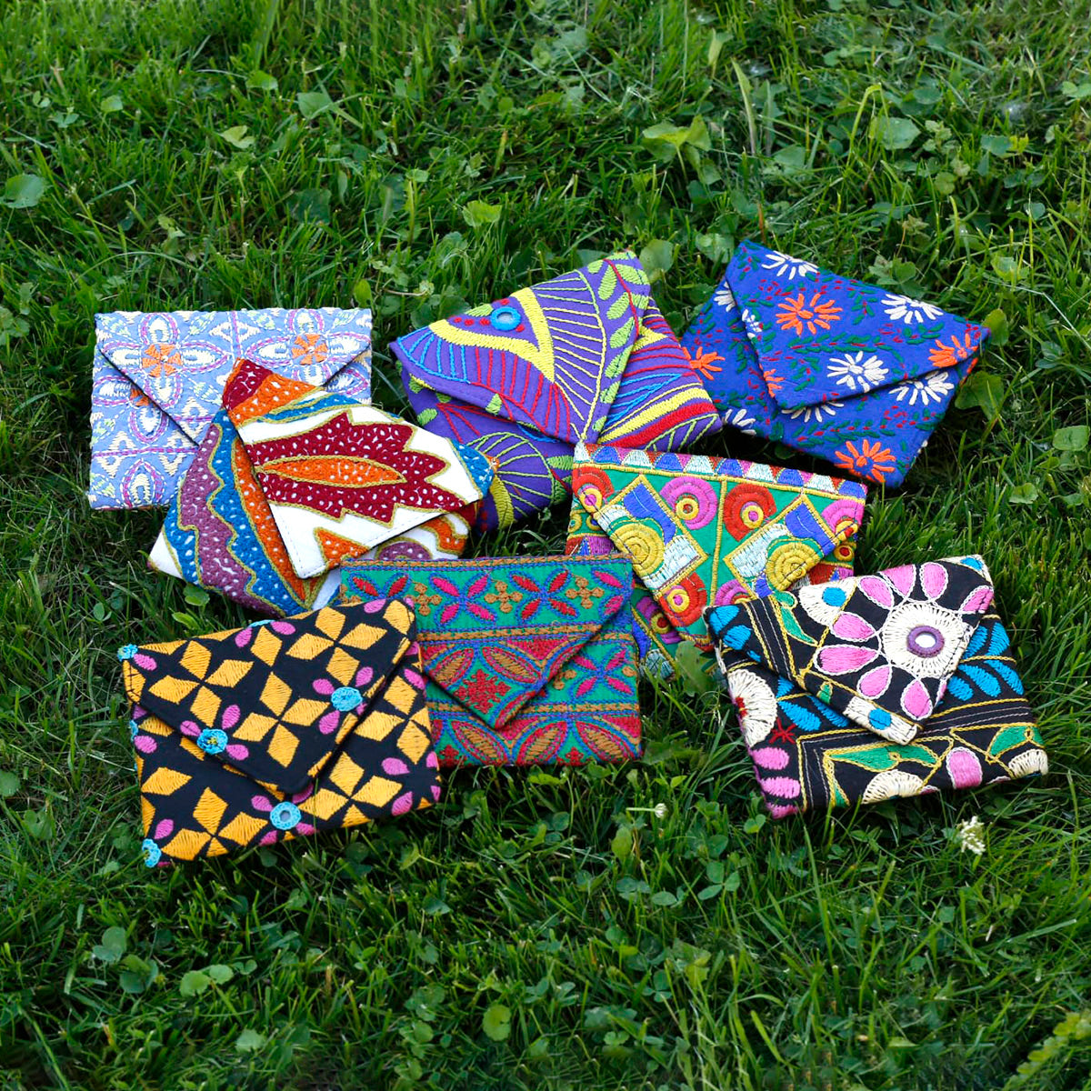 A collection of colorful envelope-style pouches is displayed on bright green grass.