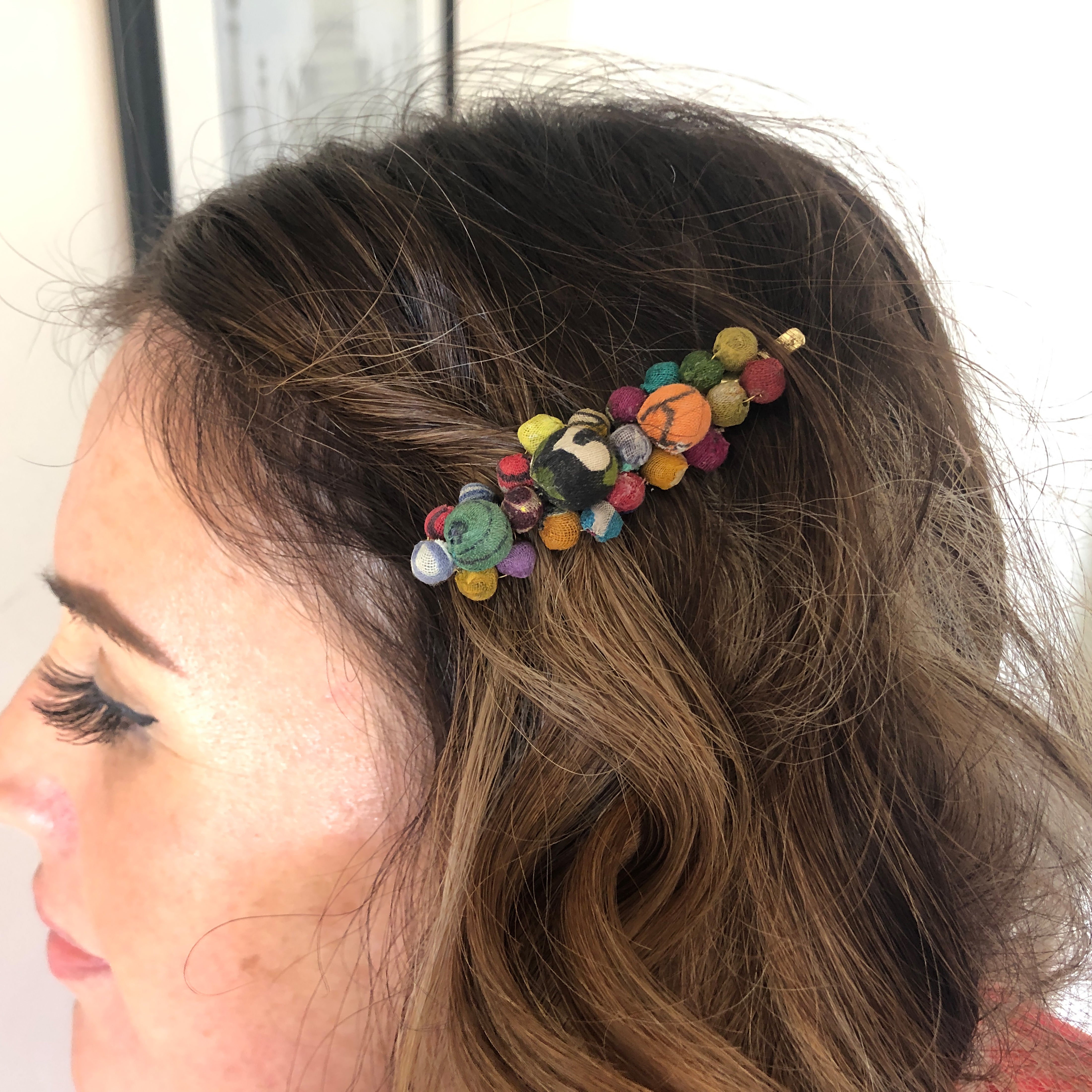 A close up of a woman's hair and the beaded multicolor hair accessory she is wearing.