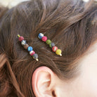 A close up of a woman's hair and the two multicolor beaded bobby pins she wears.